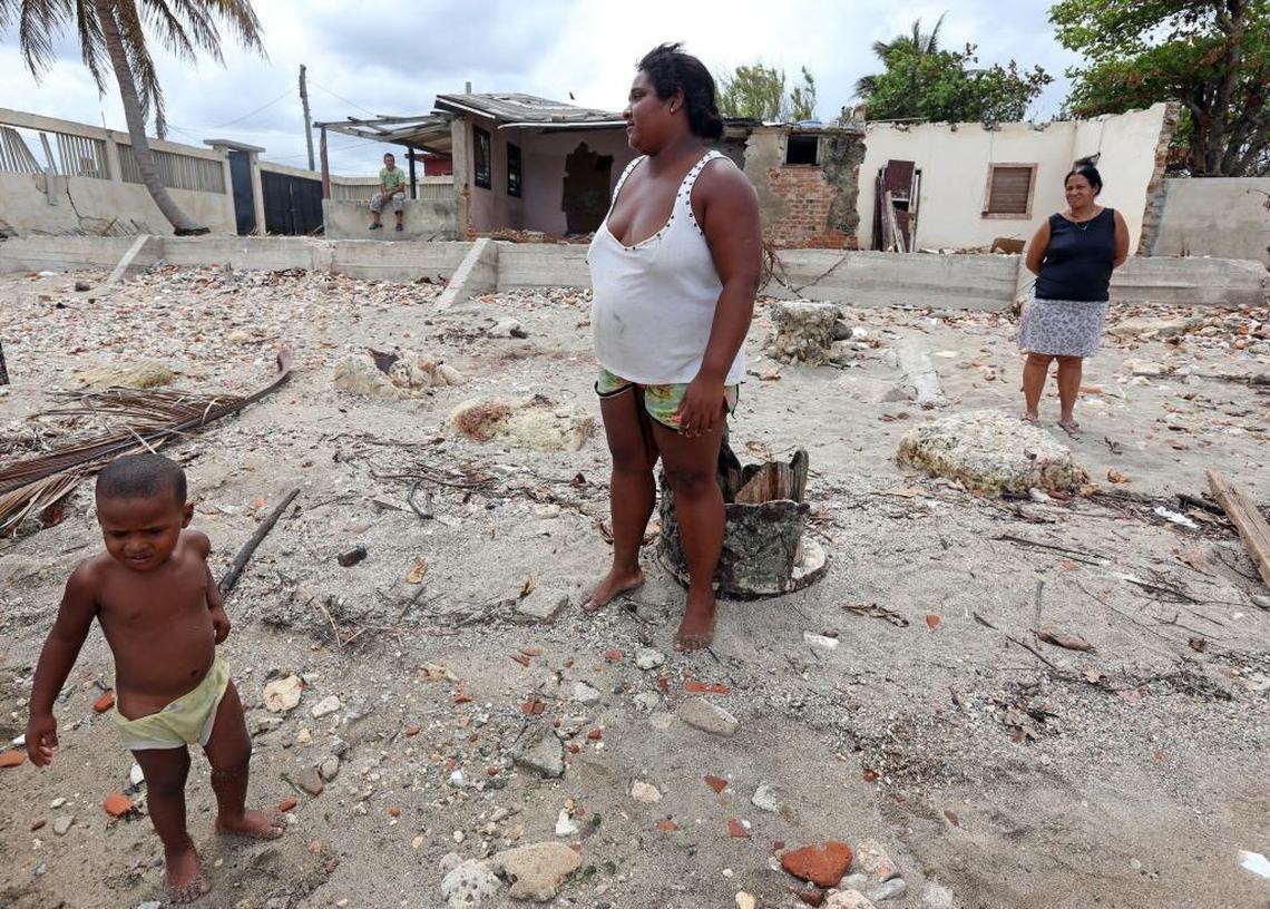 Residents of the small seaside town of Jaimanitas, Esperanza Reyes (center) and her 2-year-old son, Michael José Rodríguez, watch fishermen try to catch sardines Thursday Sept. 28, 2017 near homes damaged by the outer bands of Hurricane Irma.