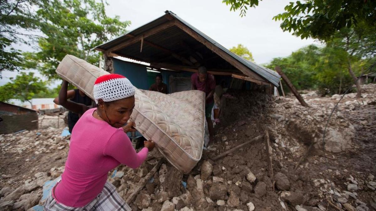 
Residents salvage a mattress from a home partially submerged in mud from a mudslide triggered by Tropical Storm Erika, in Montrouis, Haiti, Saturday, Aug. 29, 2015. Erika dissipated early Saturday, but it left devastation in its path on the small eastern Caribbean island of Dominica, and parts of Haiti authorities said. 
