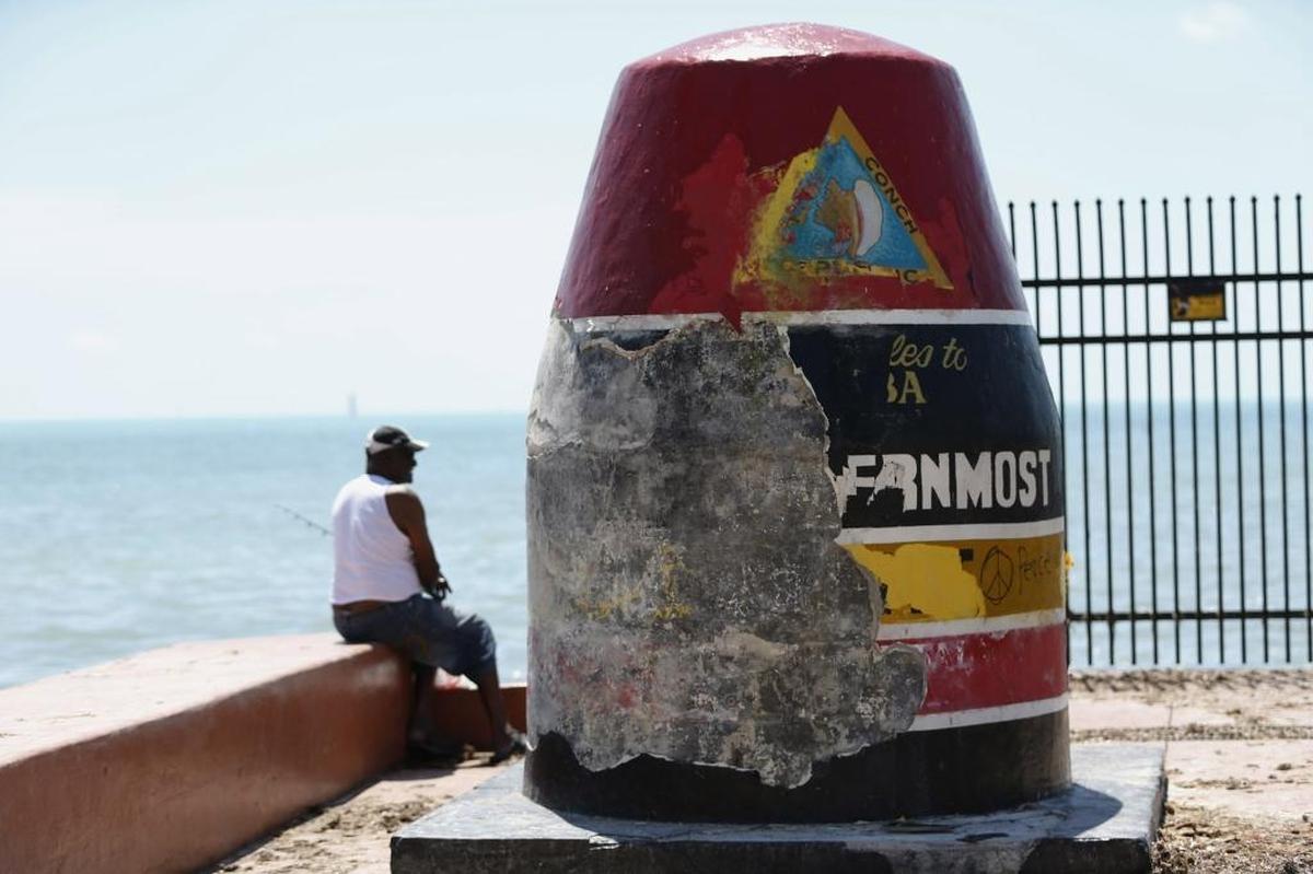 A man fishes next to the Southernmost Point Buoy damaged by Hurricane Irma, Wednesday, Sept. 13, 2017, in Key West of the Florida Keys.