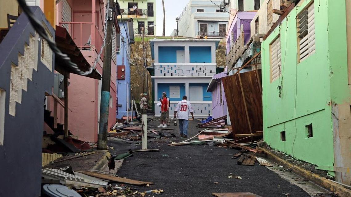 Man walks up near colorful damaged buildings. Residents of San Juan’s “La Perla” neighborhood have taken hurricane recovery into their own hands as they start the hard task of clean-up because of fear of being forgotten by the government. Hurricane Maria has left many of San Juan’s streets flooded and blocked by fallen power lines, trees, and debris as Puerto Rico tries to recover from the Category 4 storm on Thursday, Sept. 21, 2017.