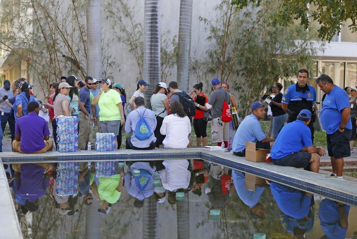 Miami Beach City employees wait to board the bus to help to clear the streets and parks of debris and trees on Wednesday.