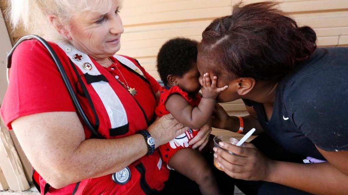 Janay Washington, right, 20, of North Miami Beach, gives her 5-month-old daughter, Ke'Lanni, a hug as Red Cross nurse Liz Miller, of Placerville, Calif., helps feed her at a Red Cross hurricane shelter set up in the Miami-Dade County Fair Expo Center on Tuesday, Sept. 19, 2017. The Washingtons were rescued as rising floodwaters surrounded their home during Hurricane Irma.