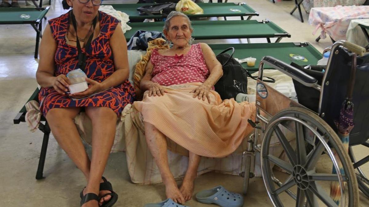 Isabela evacuee Teresa Lourdes Nunez Perez, 57, sits with her mother, Jovita Perez Velez, 90, right, as many flee due the possible breech of the Guajataca dam and find shelter at the Francisco Mendoza High School inIsabela, Puerto Rico on Saturday, September 23, 2017.