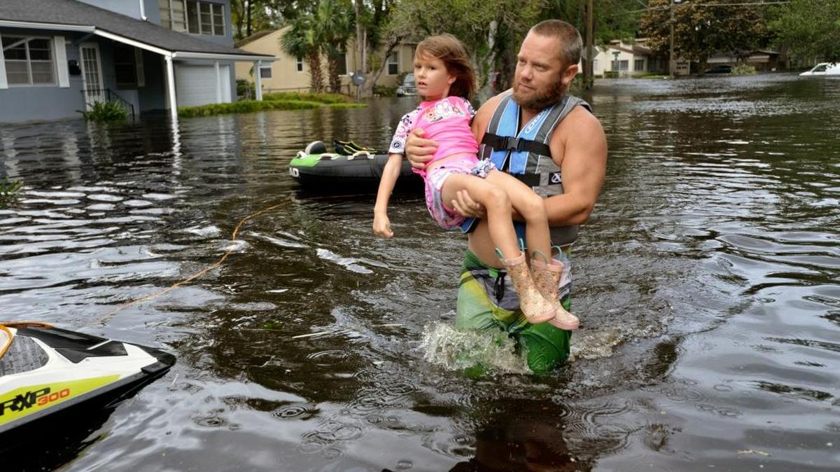 Tommy Nevitt carries Miranda Abbott, 6, through flooding caused by Hurricane Irma on the west side of Jacksonville, Monday, Sept. 11 2017.
