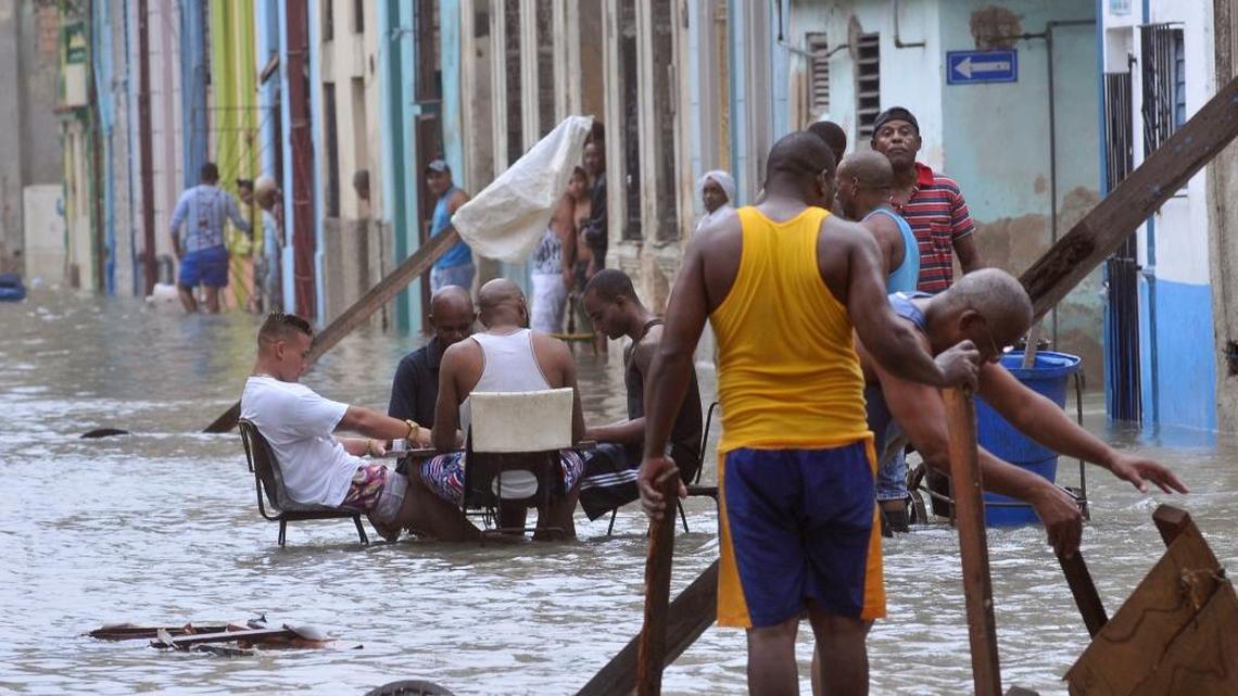 In this Sept. 10 photo released by Granma, men play dominoes in the middle of a flooded Havana street as others pull broken furniture from calf-high water in the aftermath of Hurricane Irma. Neighbors were helping each other out, and those who got tired would sit down and play dominoes.