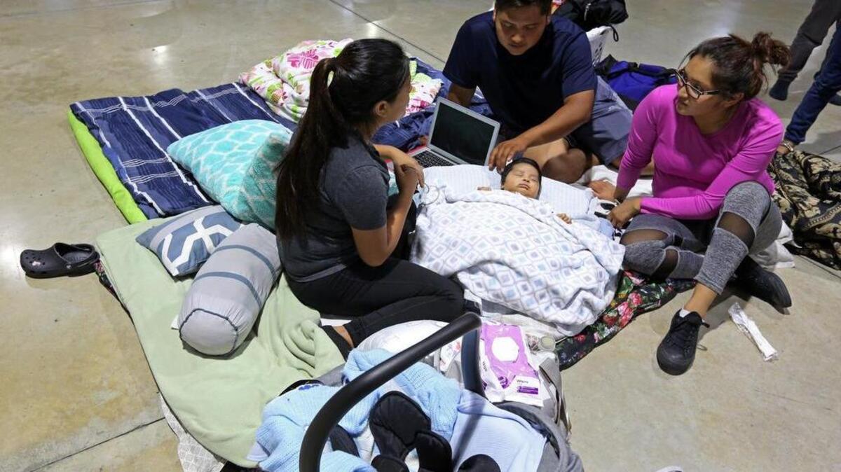 (L-R) Nelly Diaz and Albino Perez watch over their 2-month old son, Nicholas, along with his aunt, Nelly Diaz at the hurricane shelter at the Miami-Dade County Fair and Exhibition, home to the Youth Fair at Tamiami Park, 10901 Coral Way, Miami. The family and many of their relatives came to the shelter along with their pets.