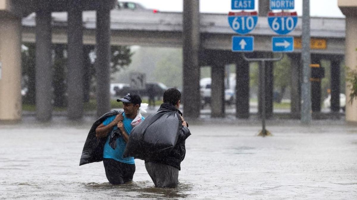 Local apartment residents cross high water on North Braeswood Blvd to escape the flooding from Hurricane Harvey August 28, 2017 in Houston, Texas. Harvey, which made landfall north of Corpus Christi late Friday evening, is expected to dump upwards to 40 inches of rain in areas of Texas over the next couple of days.