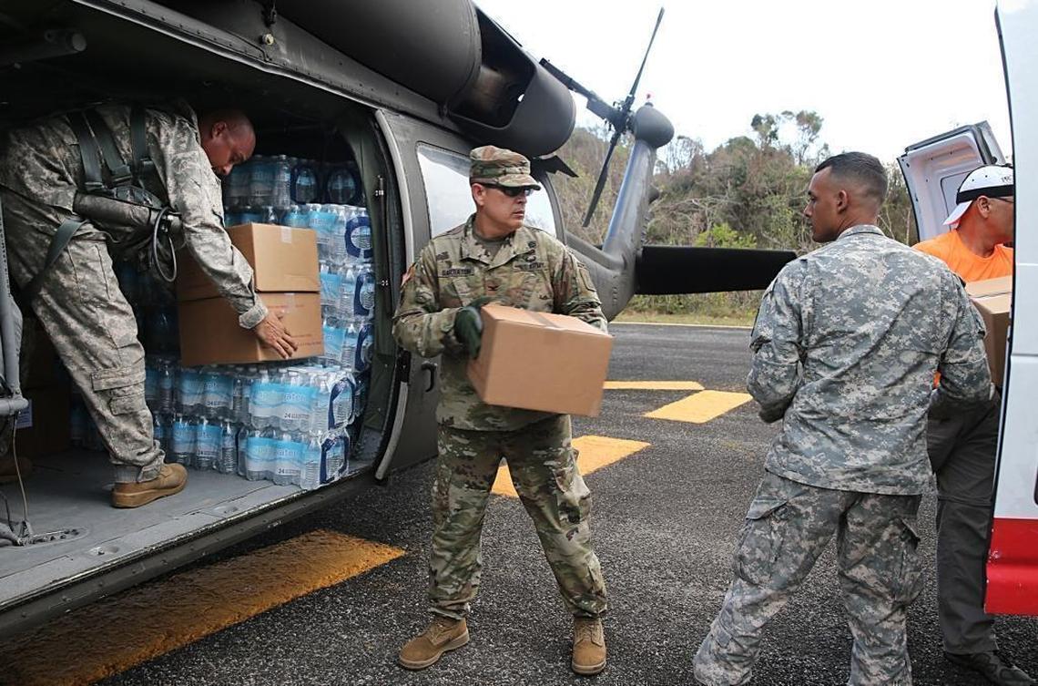 U.S. Army Col. Ricardo Garraton (center) and a group of U.S. Air Force members unload relief supplies after landing next to the Arecibo Observatory on a helicopter to deliver the supplies for an isolated town in Carso, Puerto Rico.