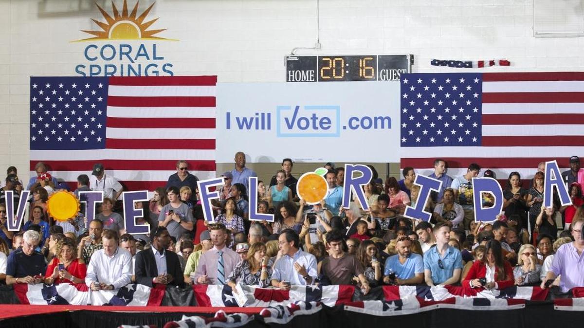 Attendees hold signs before a Hillary Clinton campaign rally at the Coral Springs Gymnasium on Friday.