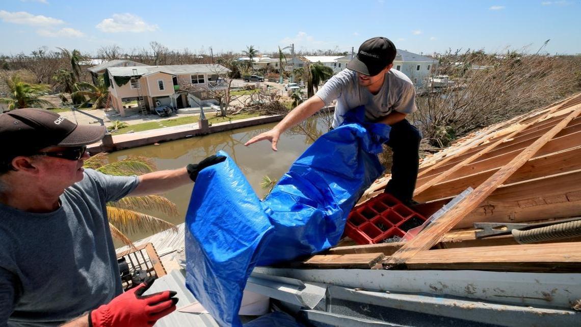 Bob Fiorile, 72, and Todd Brown, 42, left to right, pull a tarp onto the exposed roof of Fiorile's home in Big Pine Key on Sunday, September 17, 2017.