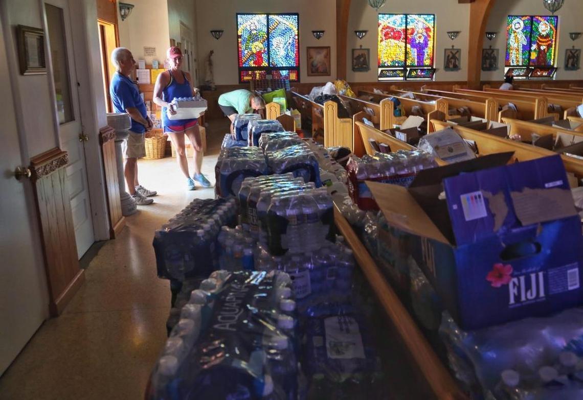 Usher Bruce Ferraro, left, stands near the open door of San Pablo Catholic Church on Marathon Key as Sandy Burton, center, and husband Rich, right, drop off water and other items donated by residents of Palm City.
