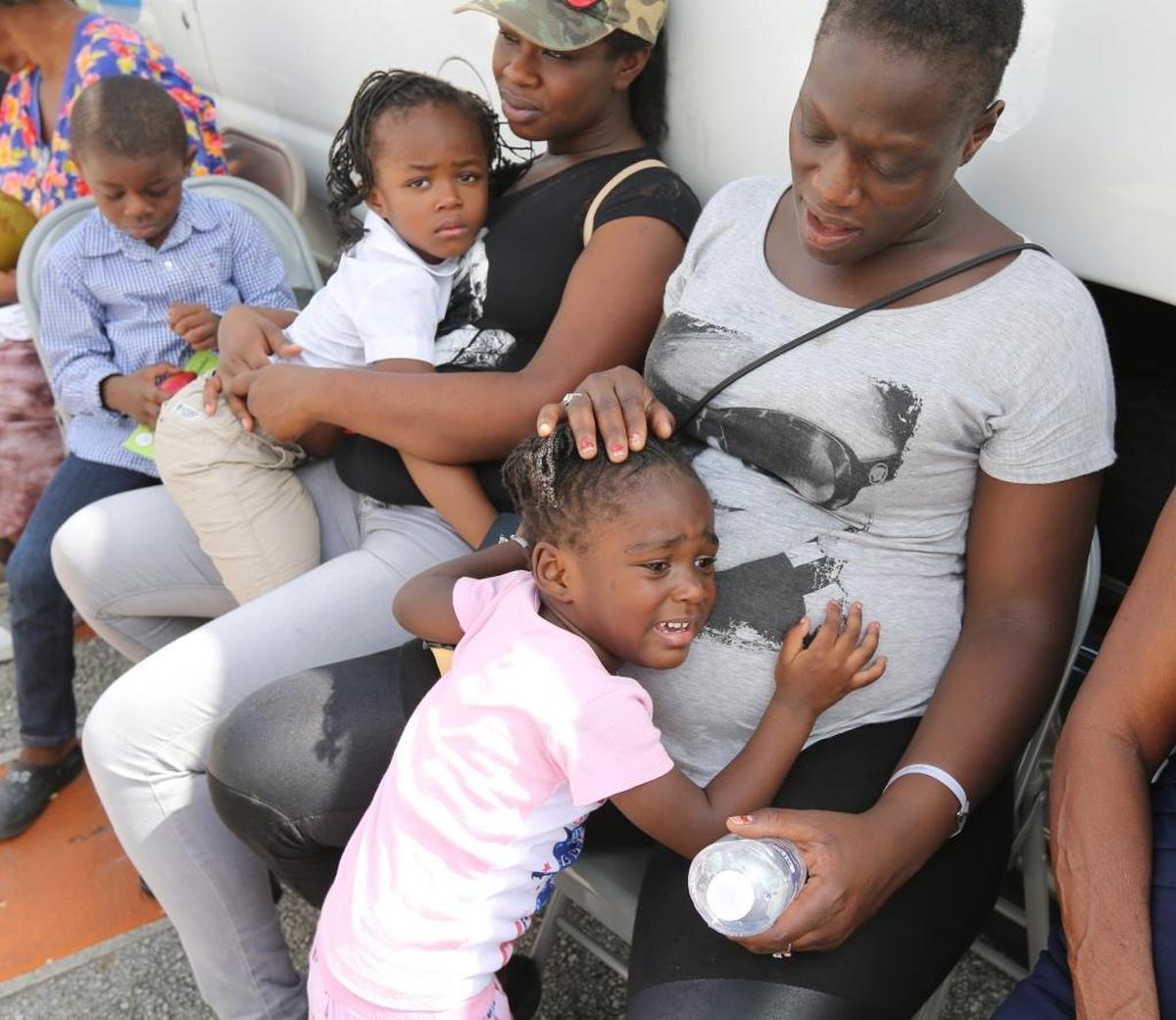 Marjorie Metellus, 35, tries to comfort her 3-year-old daughter Geneviene, as she and her new friend, Chantrell Manning, 25, and her kids, Taliyah, 4, and Robert, 5, wait in the heat outside of the E. Darwin Fuchs Pavilion at the Miami-Dade Fairgrounds, Thursday, Sept. 14, 2017.