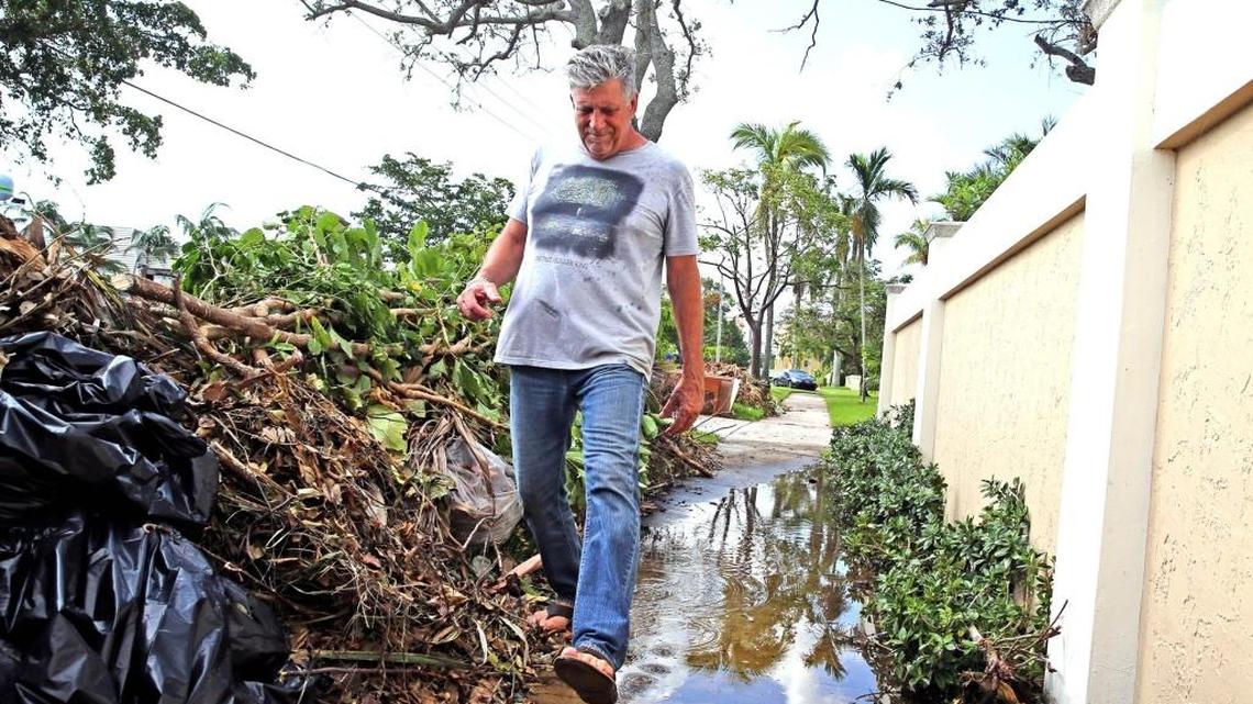 Steve Poskoski passes piles of debris from Irma as he navigates a sidewalk flooded by this week’s king tide in front of his Cordova Road home in Fort Lauderdale. Debris from the storm has clogged many storm drains.