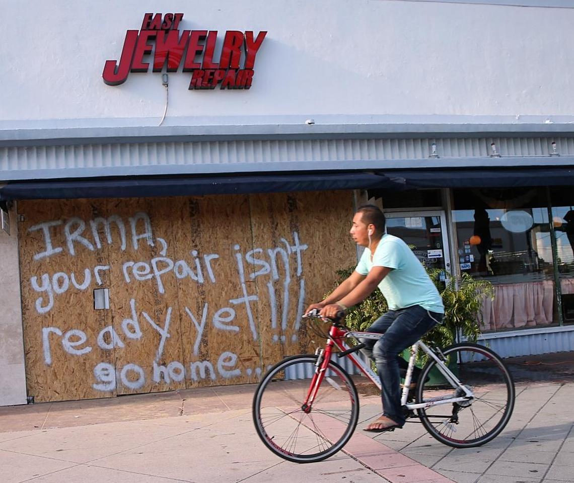 A biker rides by a message written on the plywood shutters to hurricane Irma from the owners of the Fast Jewelry Repair store in Miami Beach on September 07, 2017 as South Florida prepares for the coming hurricane Irma.