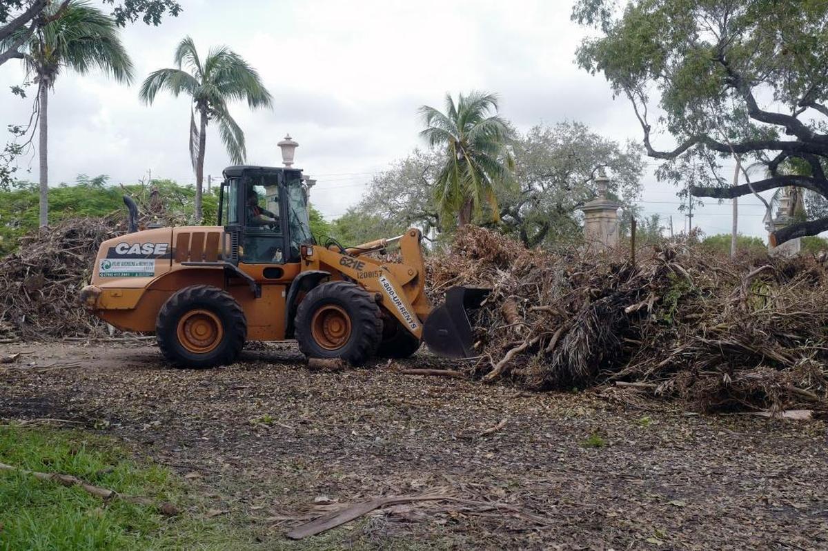 A worker picks up debris on Country Club Prado Boulevard in Coral Gables on Wednesday, September 27, 2017.
