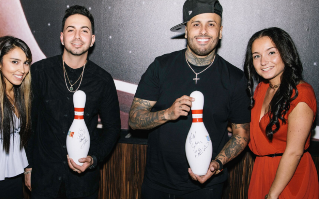 Justin Quiles and Nicky Jam pose with the autographed bowling pins they signed at KINGS Dining & Entertainment Doral