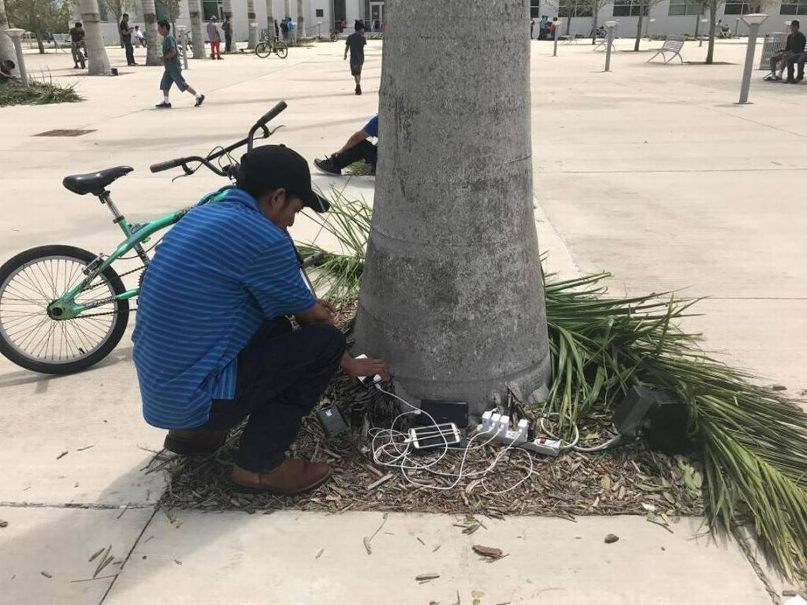 About 100 people stood outside Homestead City Hall Monday afternoon to charge their phones at several outdoor electrical outlets post Hurricane Irma.