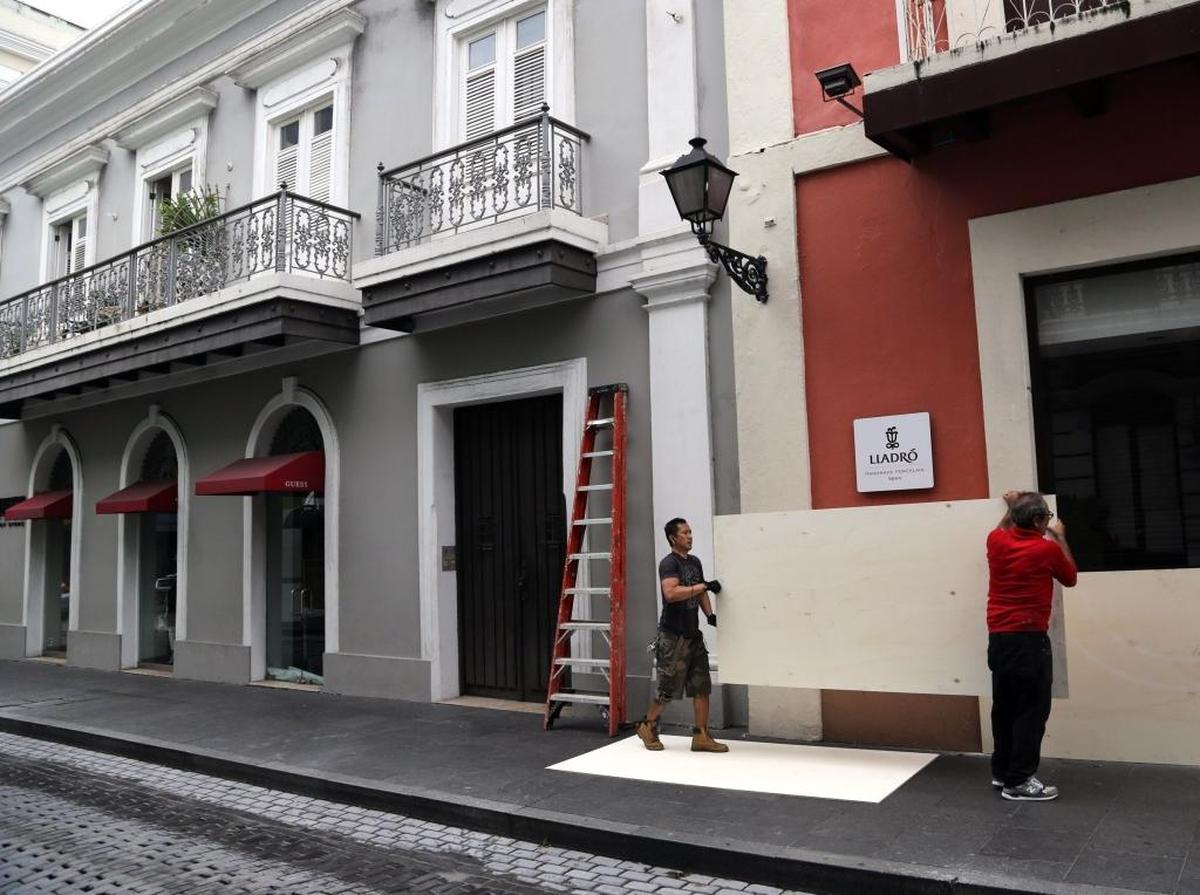 Mario Baniaga, left, and Daniel Hernandez board up windows for a client's storefront in advance of Hurricane Maria at the historic Old San Juan, Puerto Rico, on Tuesday.