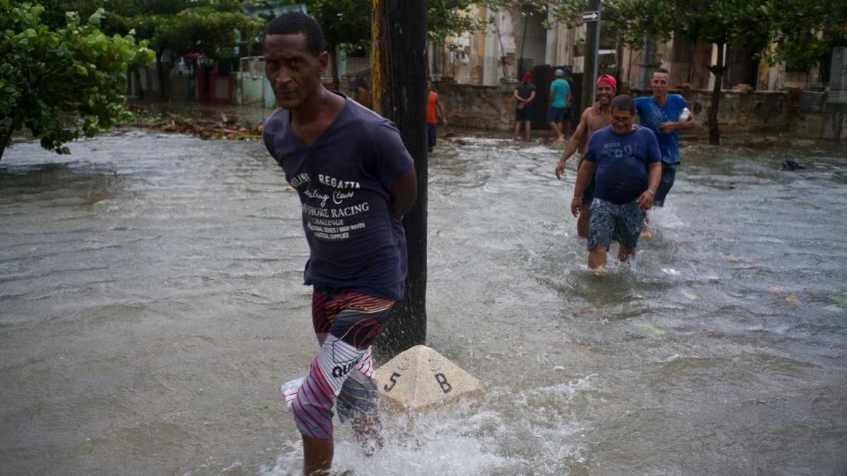 Several people try to cross a flooded street in Havana.