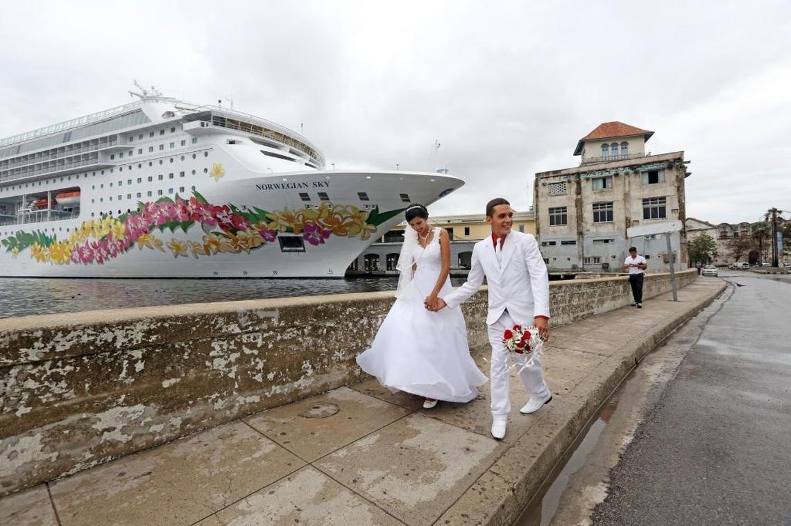 Cuban newlyweds walk hand-in-hand down a wet and windy Havana street following a photo shoot in front of the Norwegian Sky Tuesday afternoon, Sept. 26, 2017. Tourism is rebounding in Havana, with cruise ships, like the Norwegian Sky, visiting nearly three weeks since tropical storm winds from Hurricane Irma hit Havana.