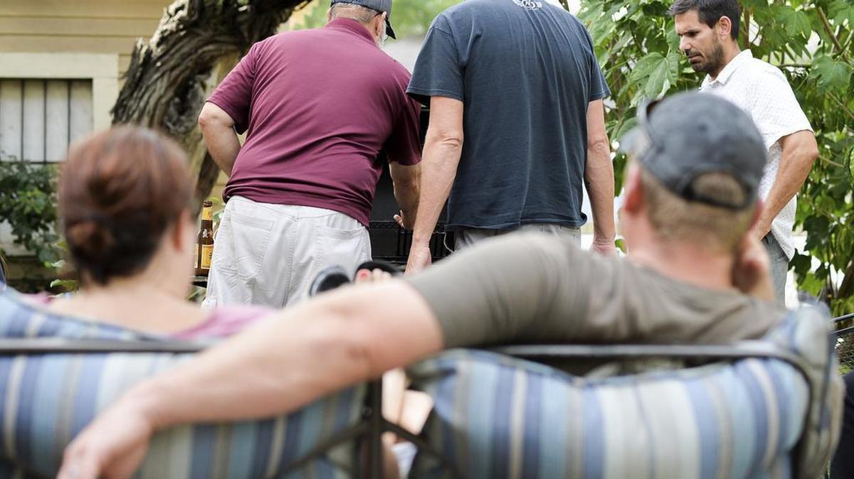 Members of the Reeves and Parker families gather in the backyard and work on starting a barbecue at a local Airbnb property on Saturday, Aug. 26, 2017, in Brownsville, Texas. The families discovered the availability of the historic Brownsville property as they searched for a place to stay after leaving Four Bluff, Texas ahead of then-Hurricane Harvey's landfall which has caused devastation near the Corpus Christi area of Texas.