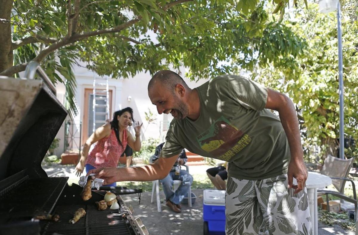 Frederico Novarese, who lives in a North Beach apartment at 75th Street and Byron Avenue, cooks chicken on the grill for his neighbors Tuesday.