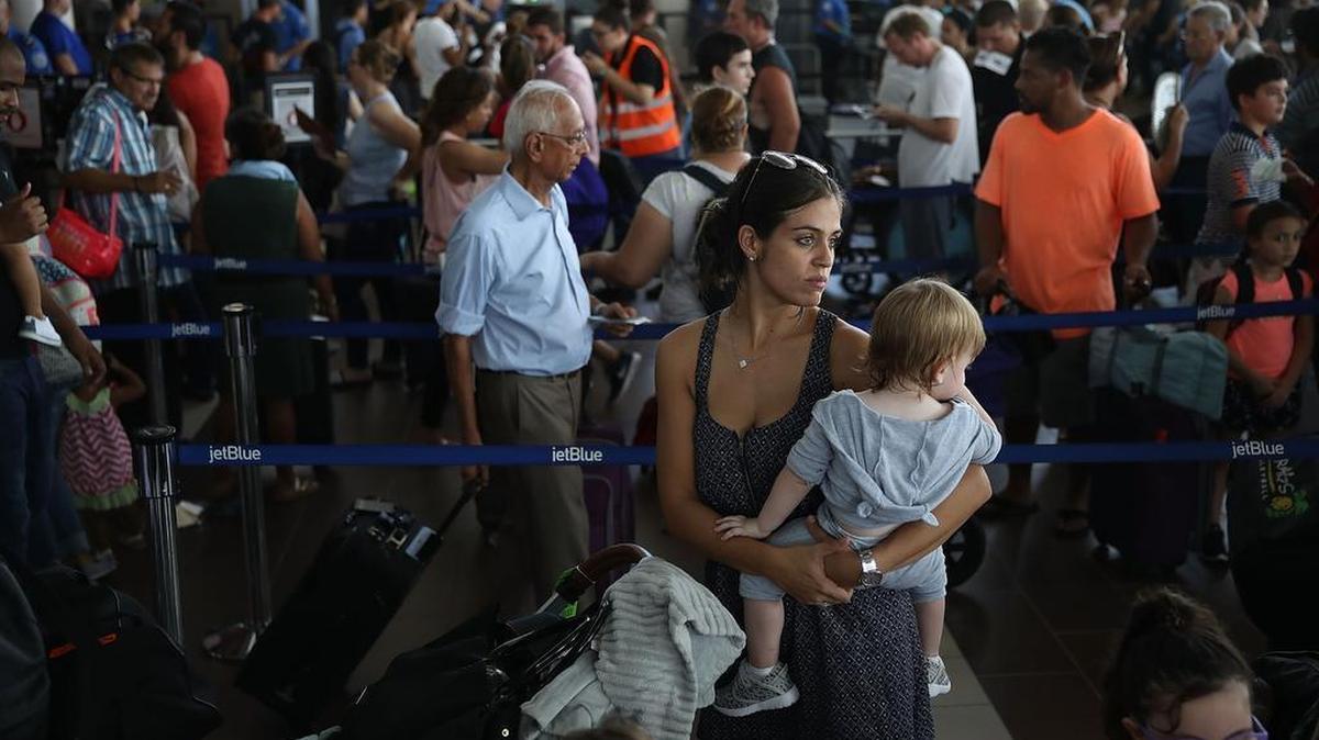 Noelia Torres and Orlando Liam Bear,1, are awaiting to go to Orlando along with other who are in line to clear through security to catch a flight out of the Luis Muñoz Marin International Airport on Sept. 26, 2017, in San Juan, Puerto Rico.