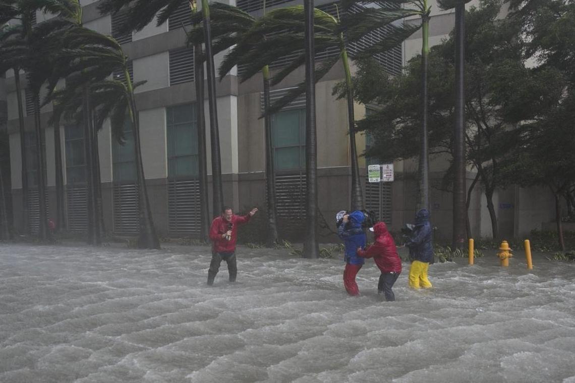 A television crew weathers the storm to broadcast from a flooded street in downtown Miami on Sunday.