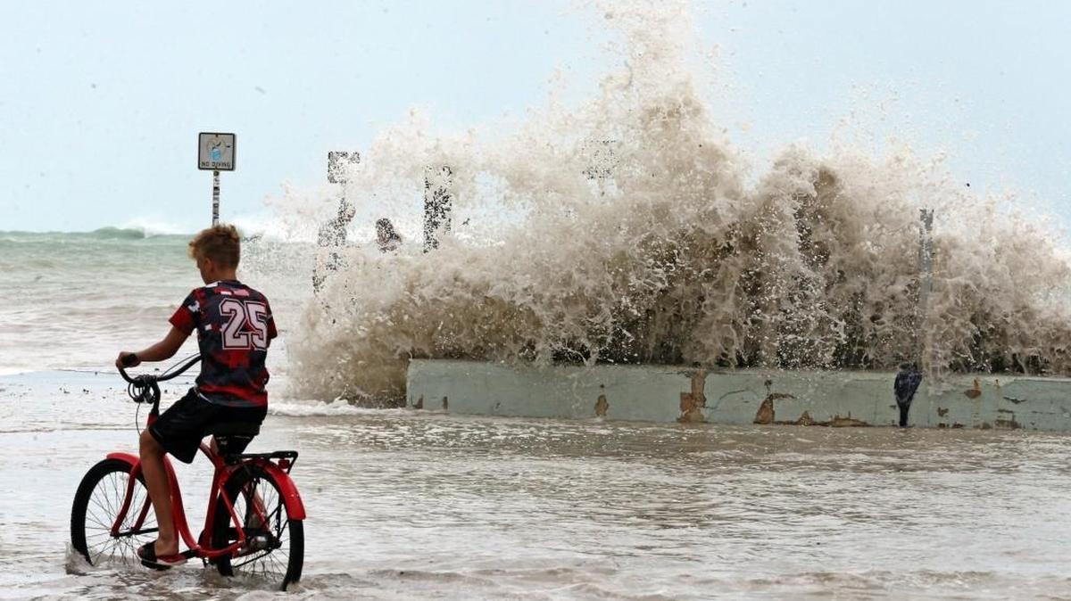 A Key West resident rides past waves crashing onto a seawall in Key West as Irma nears the Lower Keys Friday.