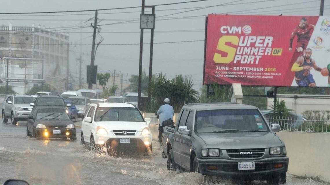 Cars drive along a street under heavy rain in downtown Kingston Jamaica, Sunday Oct. 2 , 2016.