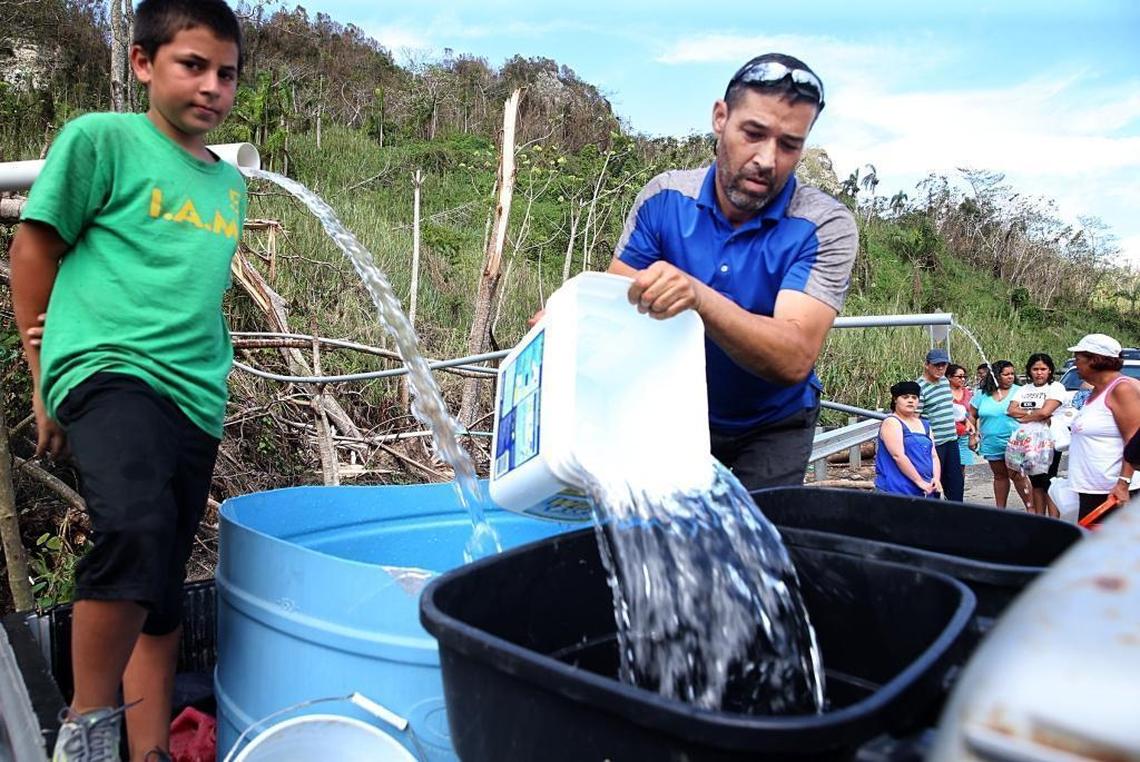 Robert Rodriguez (left) and Josue Mendez collect water from a mountain creek on a road to the town of Utuado, Puerto Rico.
