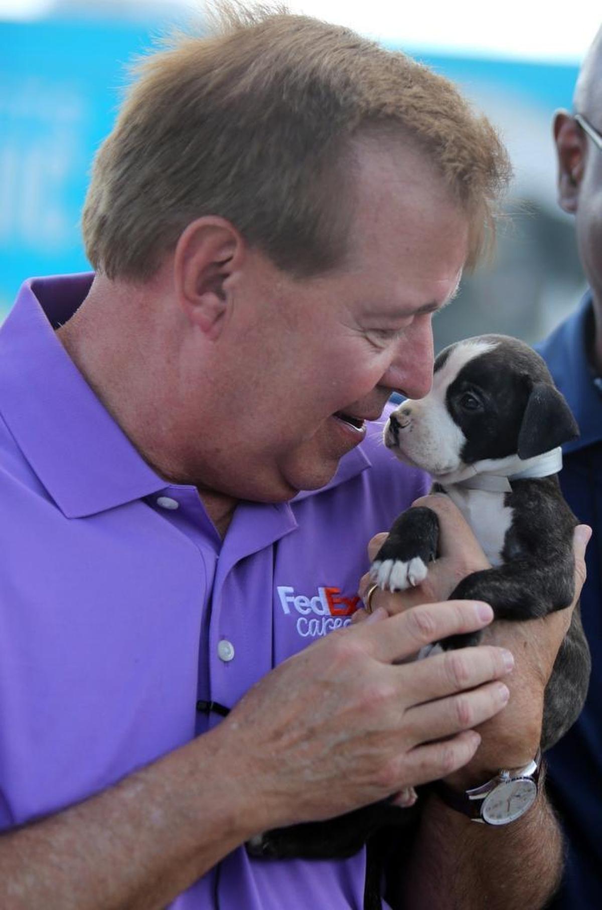 David Bronczek, president and chief operating officer of FedEx, cuddles with one of the rescue puppies about to board a plane to California.