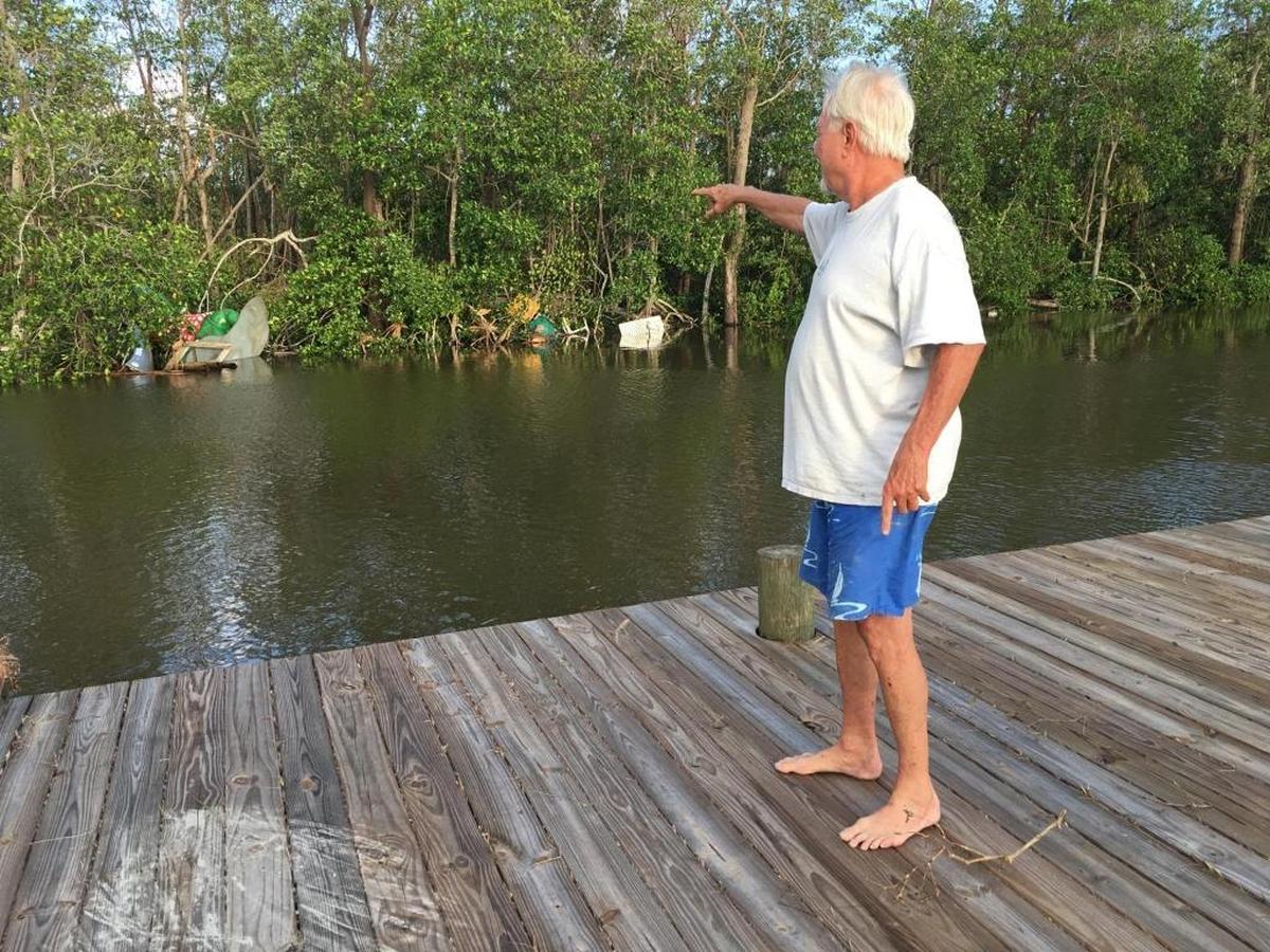 Joe West, 73, of Everglades City, points to a statue of an alligator that once fronted a shop across the street from his house, but was lifted by Hurricane Irma and deposited across the canal behind his house.