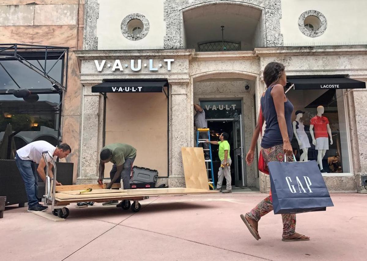 Workers board up windows at Vault, a Lincoln Road boutique, on Wednesday.