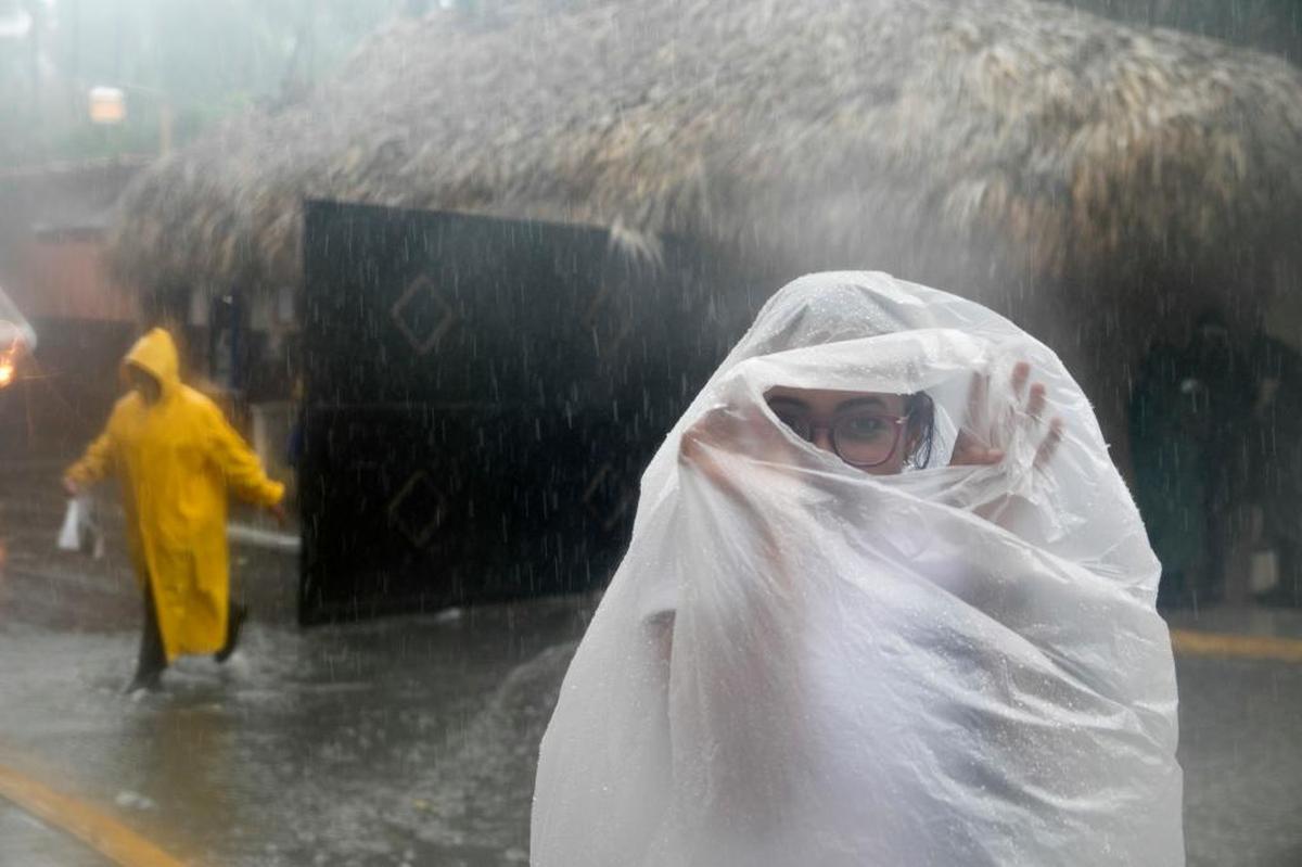 A woman covers herself with a plastic bag as she makes her way to work as Hurricane Maria approaches the coast of Bavaro, Dominican Republic, on Wednesday.