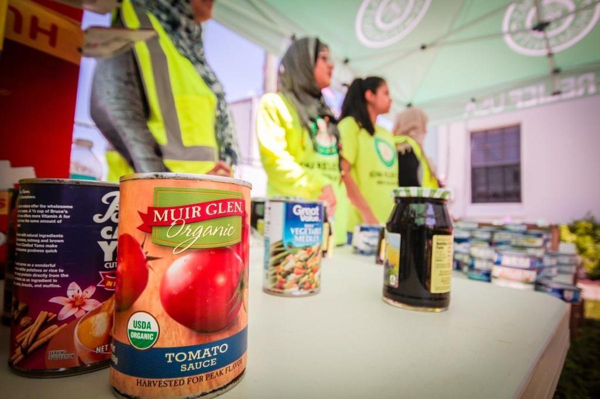 Canned goods are displayed on a distribution table as volunteers stand waiting to give out food to victims of Hurricane Irma at the Masjid Al-Ansar mosque in Miami, Fla.