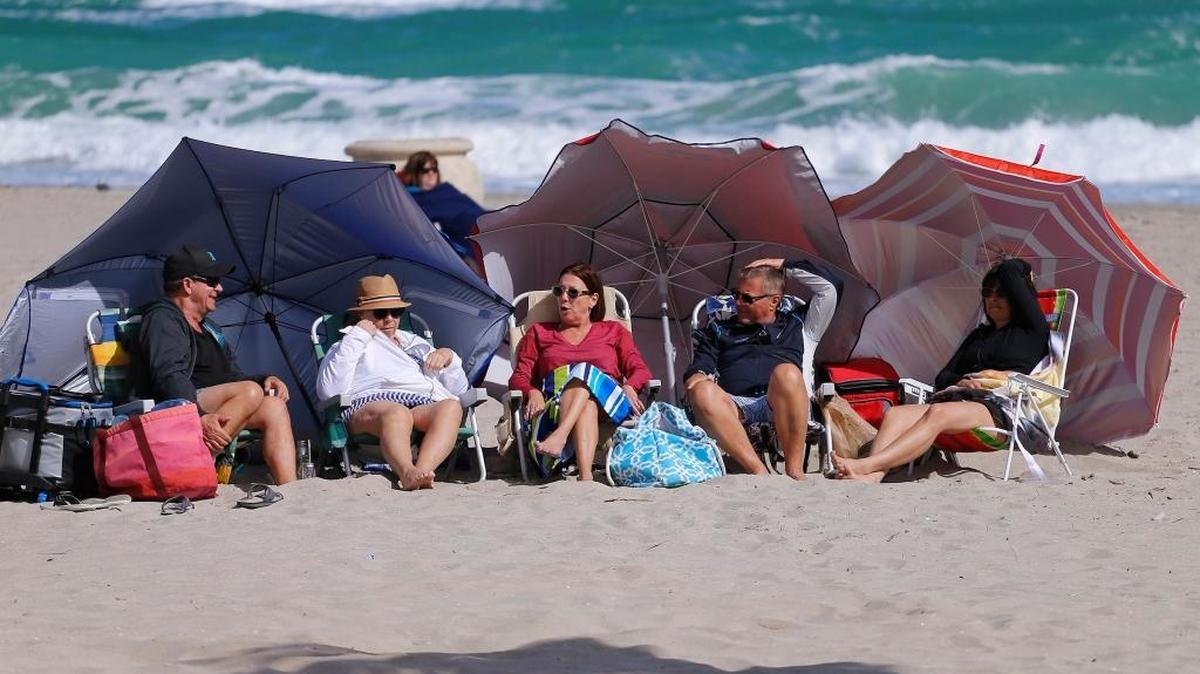 Canadian snowbirds bathe in the sunlight as the rough surf crashes against the shoreline. The temperature in Quebec, Canada at that moment was -1. Whipping winds and a temperature of 71 degrees brought snowbirds and tourists to Hollywood beach for a bit of sun and some heavy surf on Jan. 7, 2018.