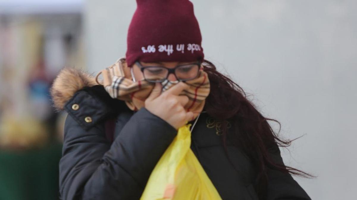 A woman covers up from the cold weather in downtown Miami on Thursday, Jan. 4, 2017.
