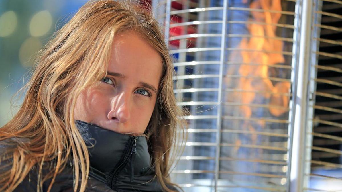 Elena Bello, vacationing from Spain, keeps warm next to a fire at the Starlite Cafe on South Beach as temperatures drop to the 40s thanks to an Arctic blast on Thursday, Jan. 4, 2018.