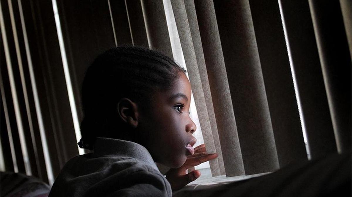 Joey Delanor Delancy, Jr., peers out the window of the Broward home he shares with his grandmother, Tandora Williams, who has raised the boy since her son was killed. Joey has a host of disabilities, including autism, bipolar disorder, ADHD and asthma.
