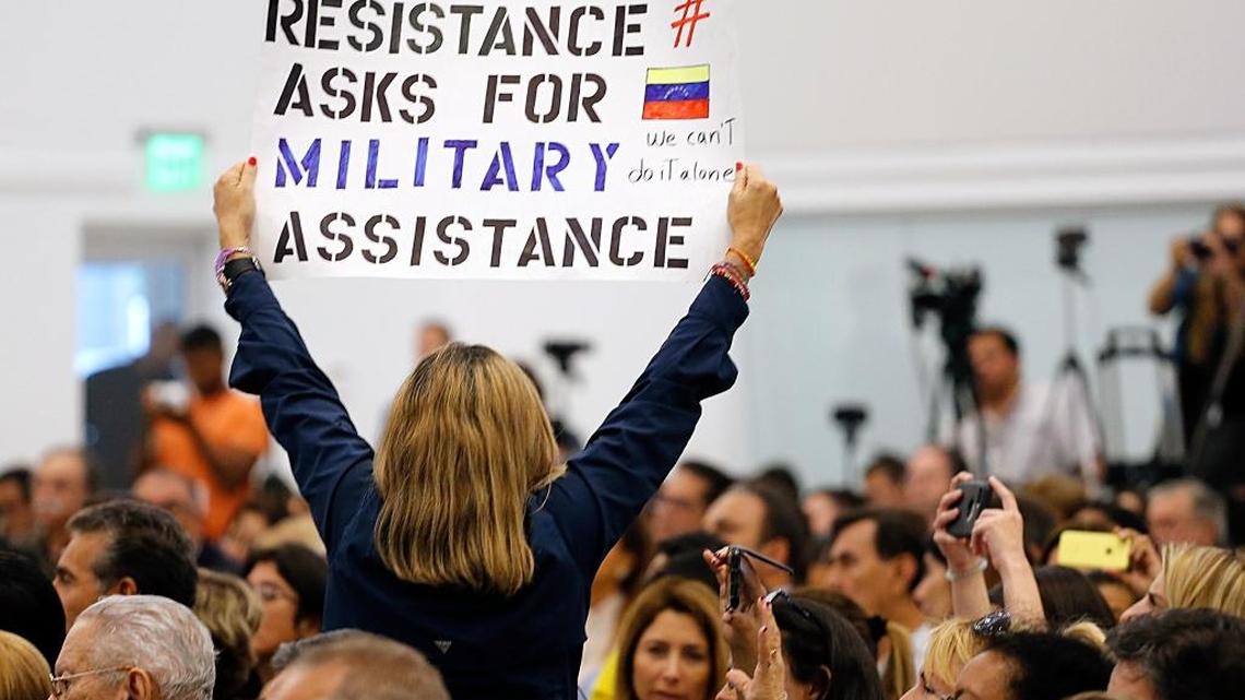 Woman holds up a sign as VP Mike Pence speaks at church in Doral: “Venezuelan Resistance asks for Military Assistance. We can’t do it alone.”