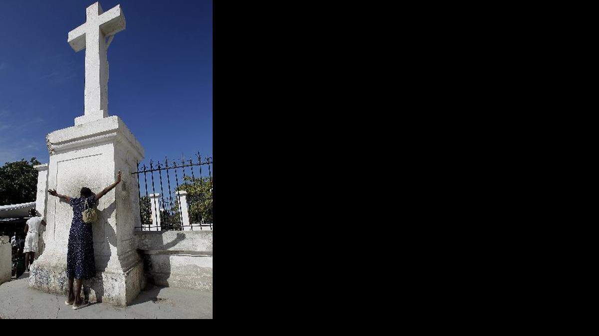 
REMEMBRANCE: A woman prays for loved ones lost in the Haiti earthquake at an undamaged cross.
