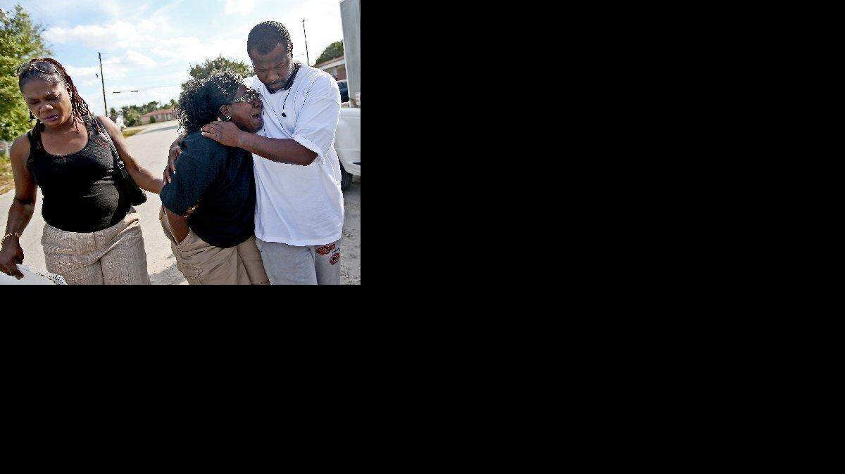 
GRIEVING: Catherine Daniels is comforted by her nephew Tyrone Nelson and her cousin Elaine Ingraham at a memorial for her son Lavall Hall in Miami Gardens.
