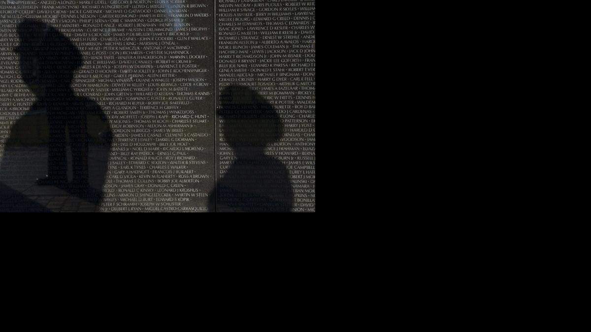 
The shadows of two Army members fall across teh Vietnam Veterans Memorial in Washington, D.C.
