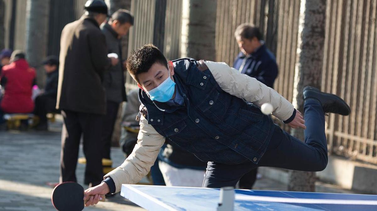 A man wore a mask while playing ping-pong outdoors in Beijing during a smog alert. Half the city’s cars were ordered off the roads.