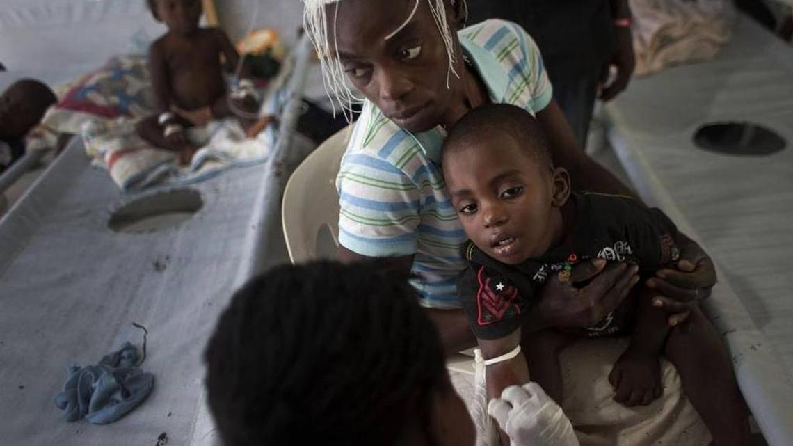 In this Oct. 19, 2011 photo, a woman holds her sick child while he receives treatment for cholera in Port-au-Prince.