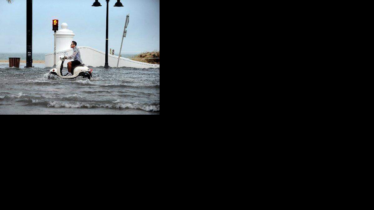 
A man rides a scooter along State Road A1A in Fort Lauderdale after torrential rains flooded the thoroughfare.
