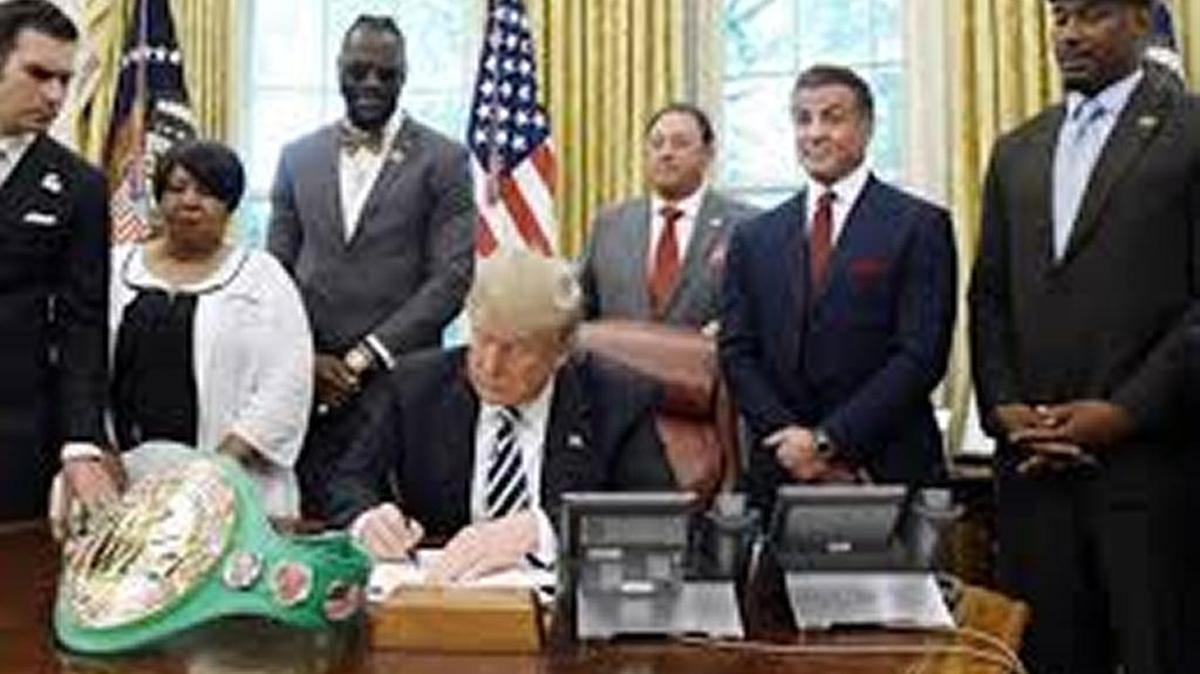 Flanked by relatives of Jack Johnson, actor Sylvester Stallone and heavyweight fighters, President Trump signs pardon.