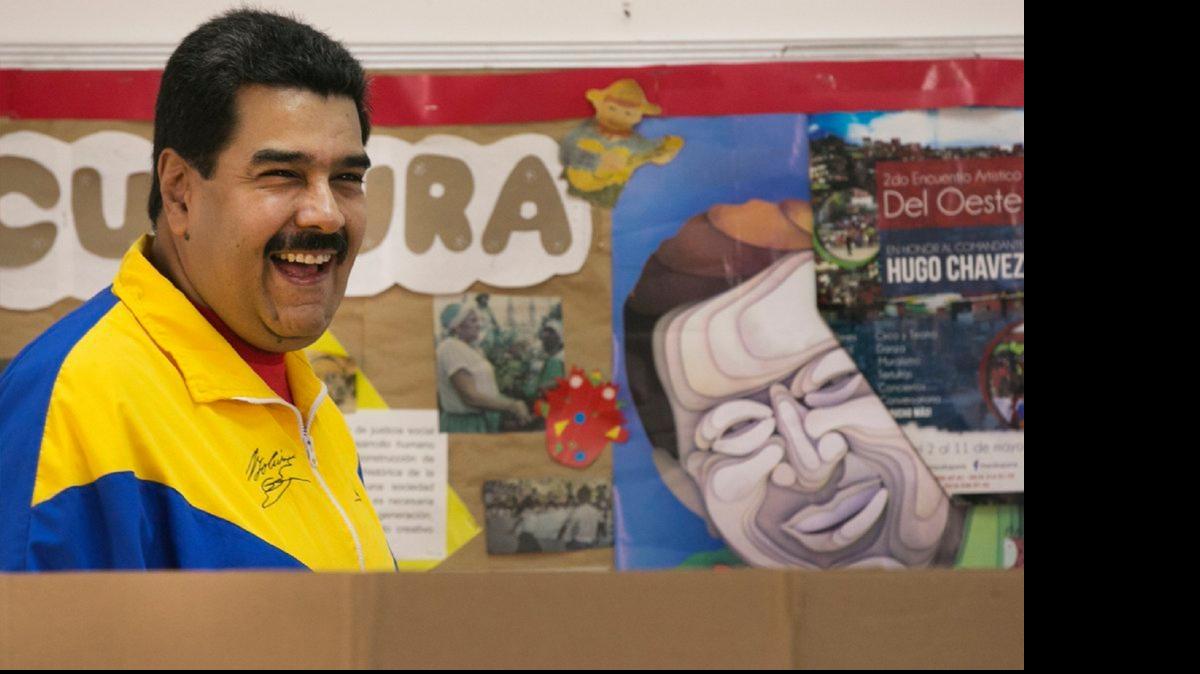 
IN CARACAS: Venezuelan President Nicolás Maduro, standing next to a poster of late President Hugo Chávez, smiles before casting his ballot during ruling-party primary elections this week.
