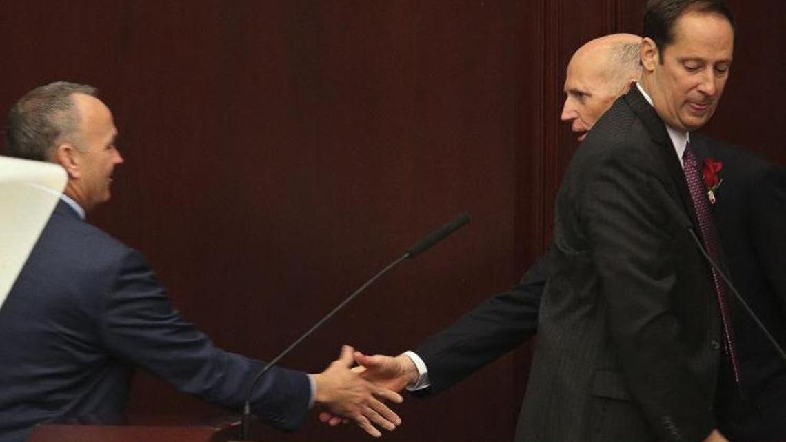 State House Speaker Richard Corcoran shakes hands with Gov. Scott. Senate President Joe Negron stands to the right.